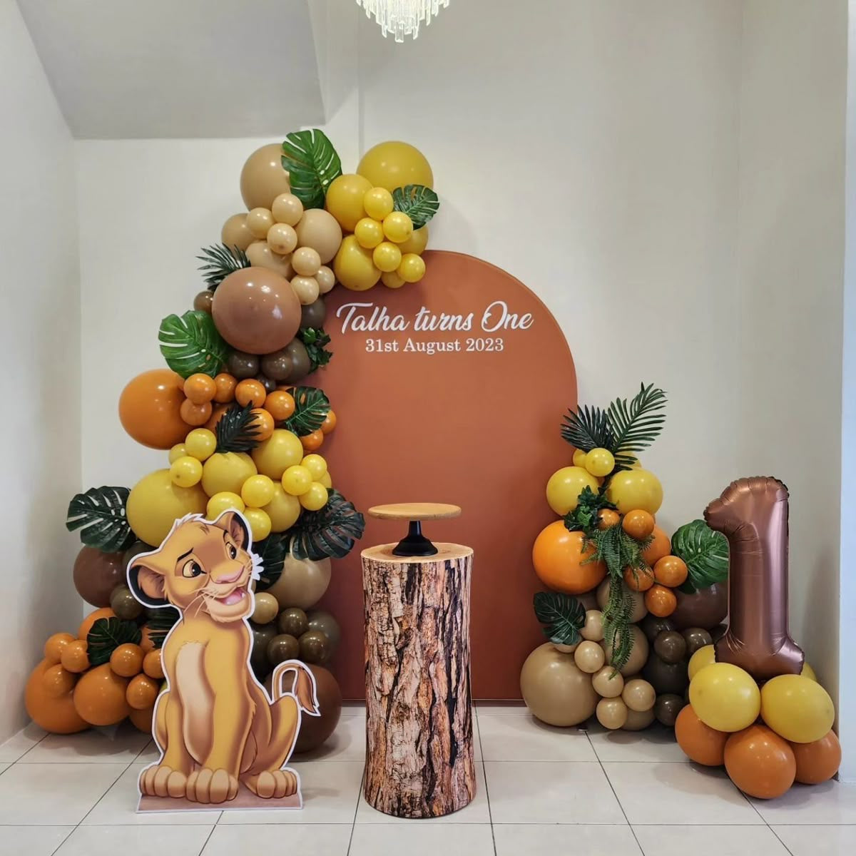 Customizable Board Jungle Backdrop with Balloon Yellow, Brown and Dust White with Number ‘1’ Balloon on Stand, Baby Lion Standee and Artificial Leaves - Safari-Themed Perfect for special occasions