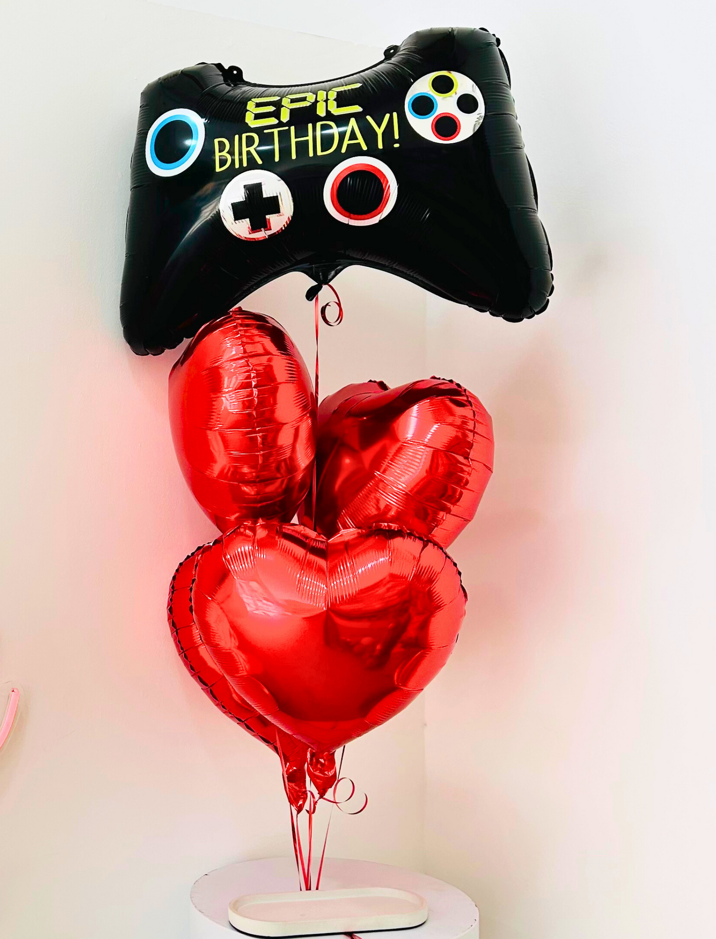 Balloon setup featuring a helium game controller balloon with 'Epic Birthday' written on it, complemented by vibrant red heart balloons Bouquet