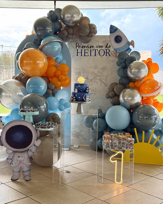 Customizable Board Backdrop with Balloons Orange, Dust White, Blue and Silver with Number ‘1’ Standee, Astronaut Standee, Rocket Accents and Acrylic Cake Stand Setup - Galaxy-Themed Perfect for special occasions