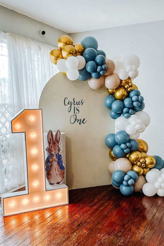 Customizable Board Backdrop with Balloon Turquoise, Dust White, White and Gold with Peter Standee in White Cake Stand and LED Marquee Number ‘1’ - The Tale of Peter Rabbit-Themed Perfect for special occasions